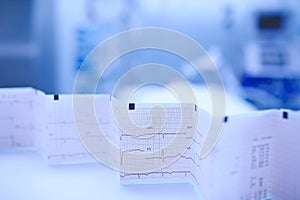 ECG chart accordion-folded on the nurse`s table on the backgroun