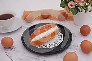 Eclair on a black plate with marble table
