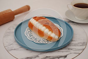 Eclair on a blue plate with marble table
