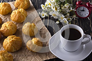 Eclair, coffee cup, alarm clock and charmomile.