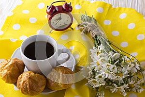 Eclair, coffee cup, alarm clock and charmomile.
