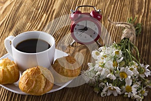 Eclair, coffee cup, alarm clock and charmomile.
