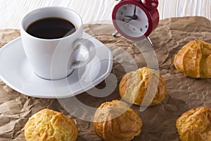 Eclair, coffee cup and alarm clock