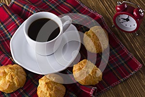 Eclair, coffee cup and alarm clock