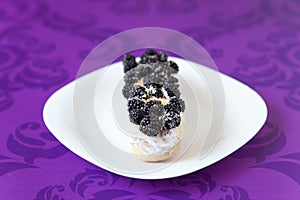 Eclair with cream and blackberies