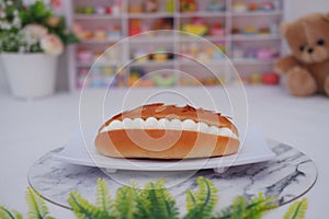 Eclair on a white plate with marble table