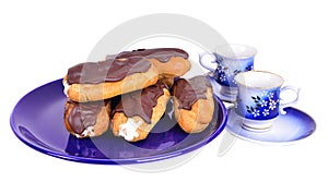 Eclairs on blue plate with coffe cups