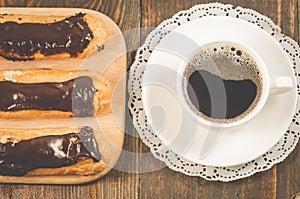 Eclairs with chocolate and a coffee cup/eclairs with chocolate a