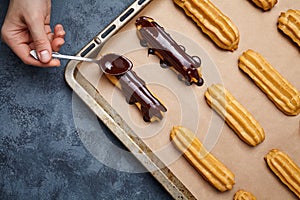 Eclairs with chocolate and whipped cream preparing on baking sheet