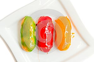 Eclairs with colorful caramel glaze on white plate