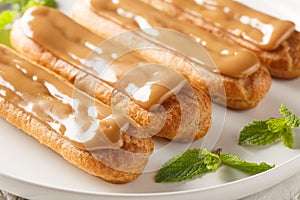 Eclairs with custard and caramels icing topped close-up in a plate. Horizontal