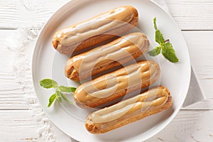Eclairs with custard and caramels icing topped close-up in a plate. Horizontal top view