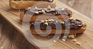 Eclairs with hazelnuts on wood board