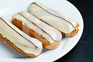 Eclairs with white icing on a plate