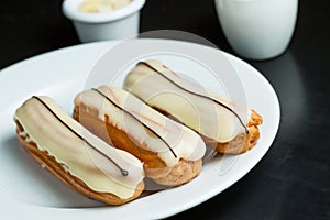 Eclairs with white icing on a plate