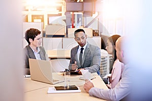 Eclectic group of four business professionals conducting a meeting