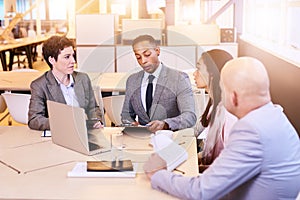 Eclectic group of four business professionals conducting a meeting