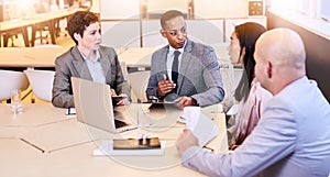 Eclectic group of four business professionals conducting a meeting