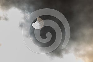 Eclipse view through clouds showcasing the moon partially covering the sun