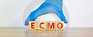 ECMO symbol. Concept words `ECMO, Extra Corporeal Membrane Oxygenation` on cubes on a beautiful white background. Doctor hand in photo