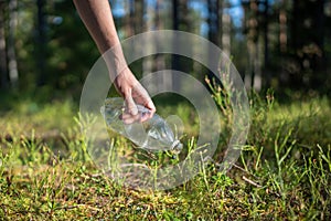 Eco activist in forest find trash left behind, picks up plastic bottle to preserve environment clean