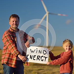 Eco activists with banner `Wind Energy` on background of power stations for renewable electric energy production.