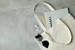 Eco bag with copybooks, headphones and sunglasses on gray background