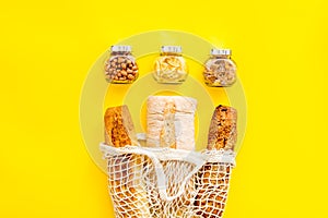 Eco bag, glass jars on yellow background, top view. Zero waste food storage concept