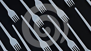 Eco concept. Plastic disposable forks stacked in rows on a black background rotate in a circle. Pattern