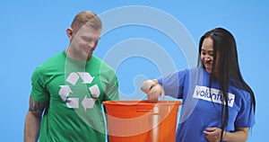 Eco-conscious man and woman putting bottle into bucket