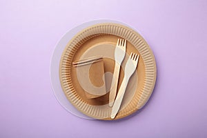 Eco craft paper tableware. Paper cups, dishes, bag, fast food containers and wooden cutlery on purple background. Zero waste.