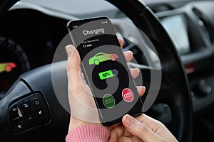 Eco electric car women hand holding phone with charging battery