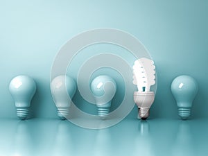 Eco energy saving light bulb , one glowing fluorescent lightbulb standing out from unlit incandescent bulbs reflection on green