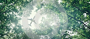 Eco-friendly air transport concept. The plane flies in the sky against the background of green trees. Environmental pollution.