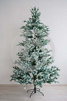 Eco-friendly artificial tree for the new year. A bare Christmas tree without decorations is standing against a white