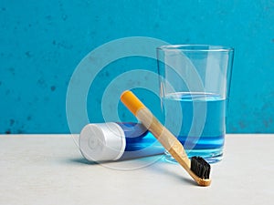 Eco friendly bamboo toothbrush, toothpaste and a glass of mouthwash on bathroom counter