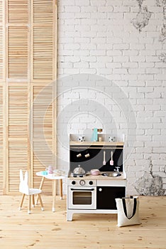 Eco-friendly children room furniture. White wooden play kitchen with oven, sink and stove, table and chair in studio copy space