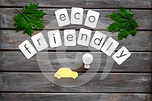 Eco friendly copy with green maple leaves, car figure and lamp for ecology concept on wooden background top view