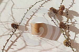 Eco friendly craft paper cup on pastel background with branch with cone and shadow. Recycling concept. Zero waste theme branch