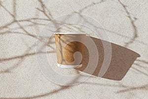 Eco friendly craft paper cup on pastel background with tree branch shadow. Recycling concept.