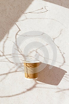 Eco friendly craft paper cup on pastel background with tree branch shadow. Recycling concept.