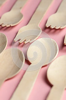 eco-friendly and disposable kitchenware pattern. wooden spoons and forks at pink coral background