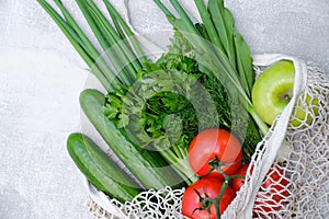Eco friendly grocery bag with vegetables and fruits on concrete stone table. Top view shopping bag with cucumbers, tomatoes,