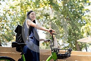 Eco friendly, Happy lifestyle asian beautiful young businesswoman riding bicycle go to office work at city street with