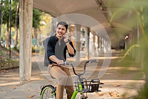 Eco friendly, Happy lifestyle asian young businessman ride bicycle go to office work at city street with bicycle in