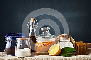 Eco-friendly natural cleaners: baking soda, soap, vinegar, salt, coffee, lemon and brush on table. Dark background