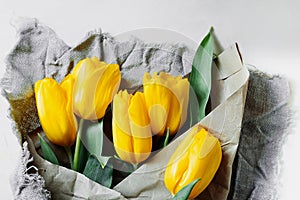 Eco-friendly reusable craft paper and fabric packaging and bouquet of fresh yellow tulips. reasonable consumption, reasonable