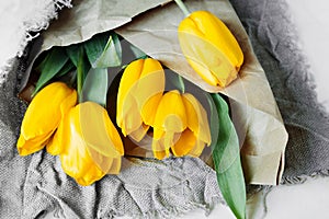 Eco-friendly reusable craft paper and fabric packaging and bouquet of fresh yellow tulips. reasonable consumption, reasonable