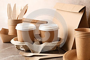 Eco - friendly tableware and paper bag on grey table