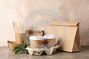 Eco - friendly tableware and paper bag on grey table